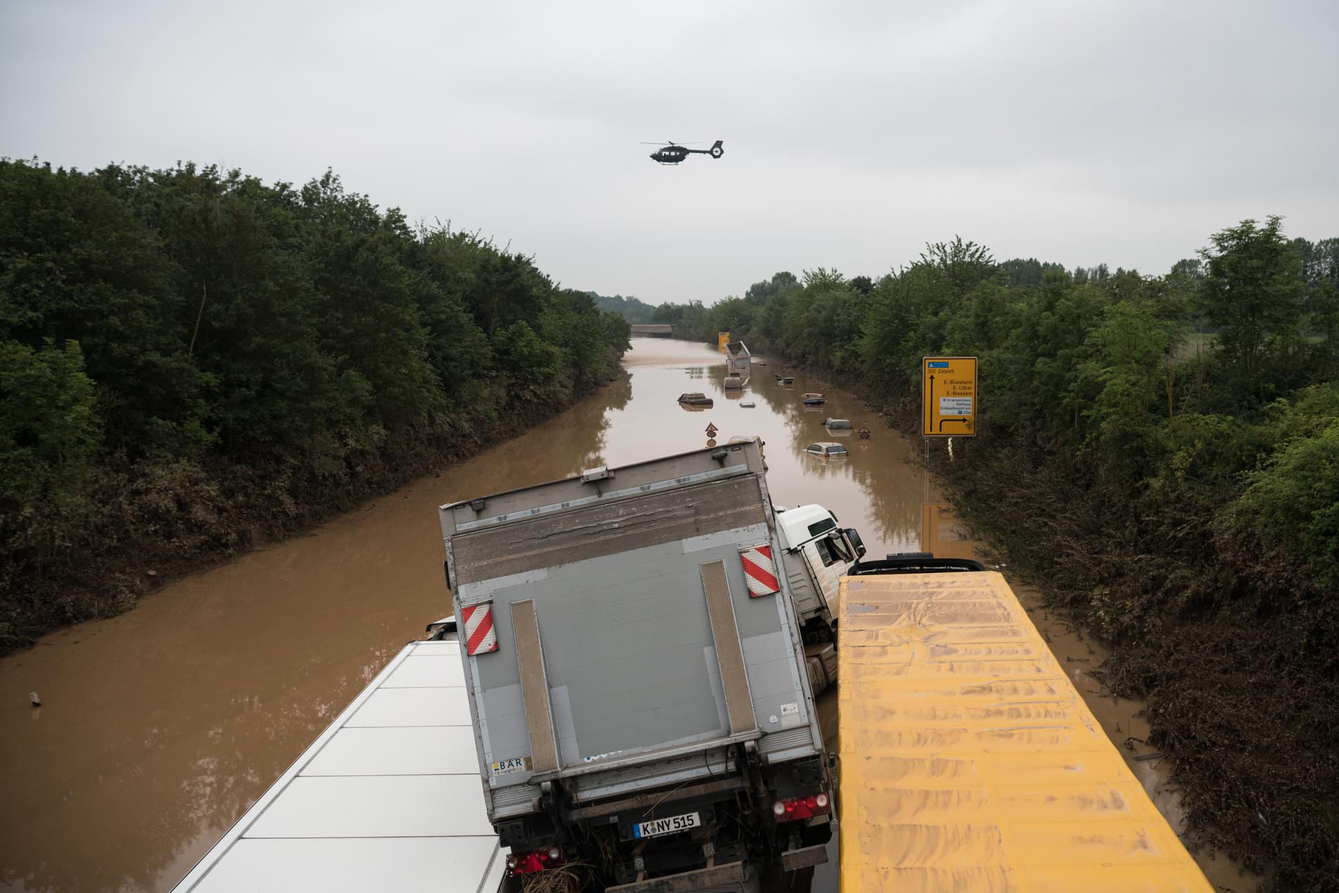 Lastbilar ligger fastkilade på en totalt översvämmad väg i Tyskland.