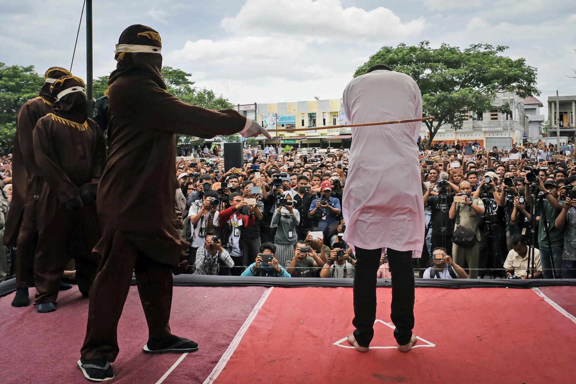 En man som dömts för att ha haft sex med en annan man pryglas under en offentlig piskning i Banda Aceh. Bilden är från i maj 2017.