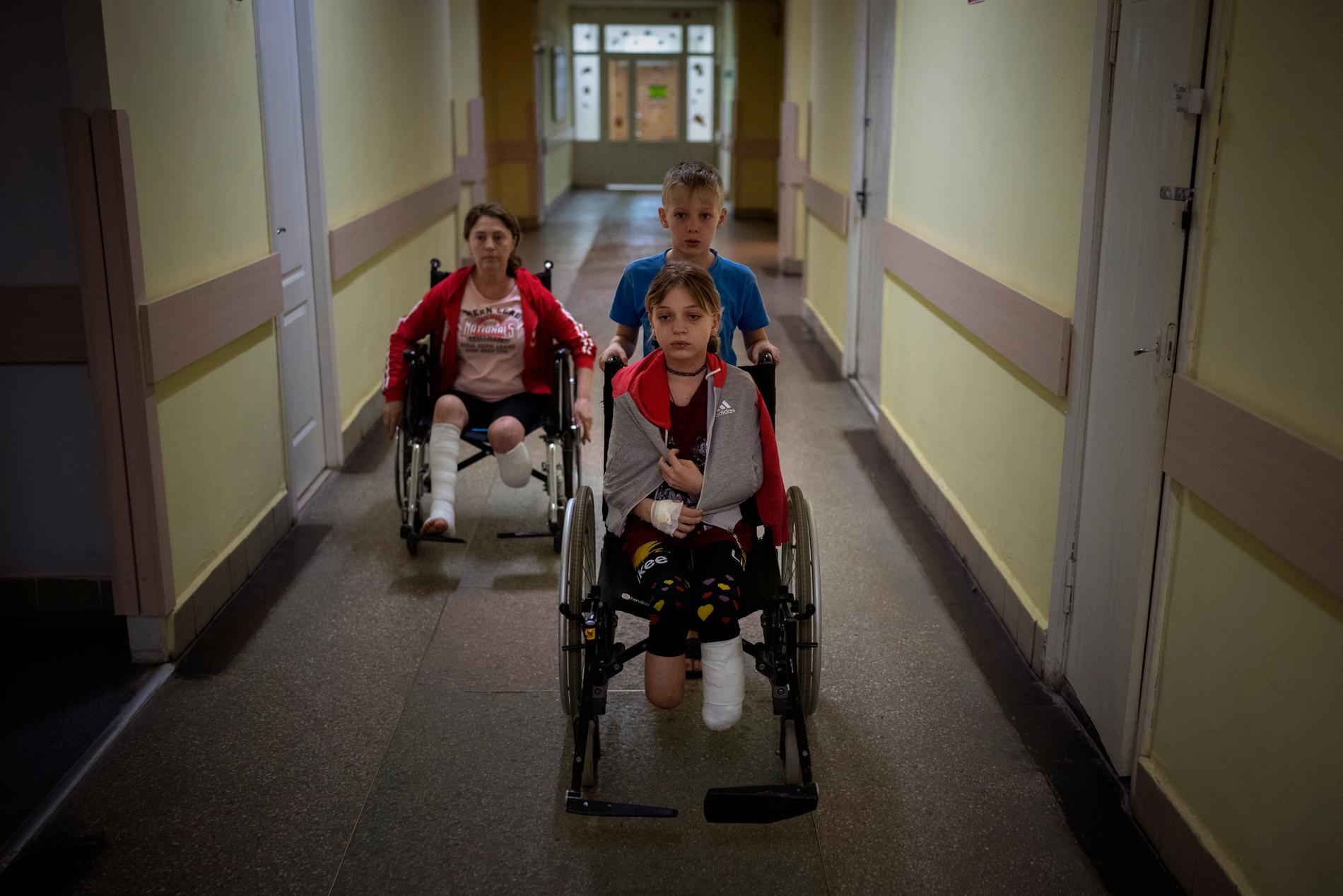 Tvillingbrodern Jaroslav hjälper systern Jana att ta sig fram på sjukhuset i Ukraina, medan mamma Natalja rullar bredvid.