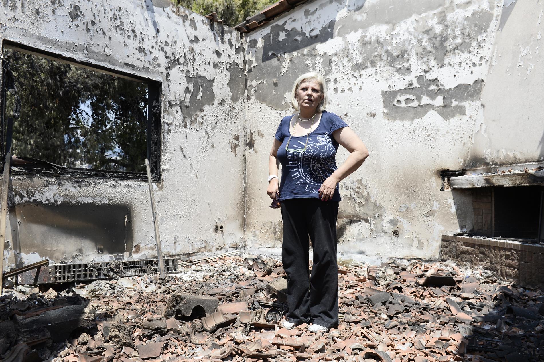 Despina Didtsi, 58, visar upp sitt nedbrända hus.