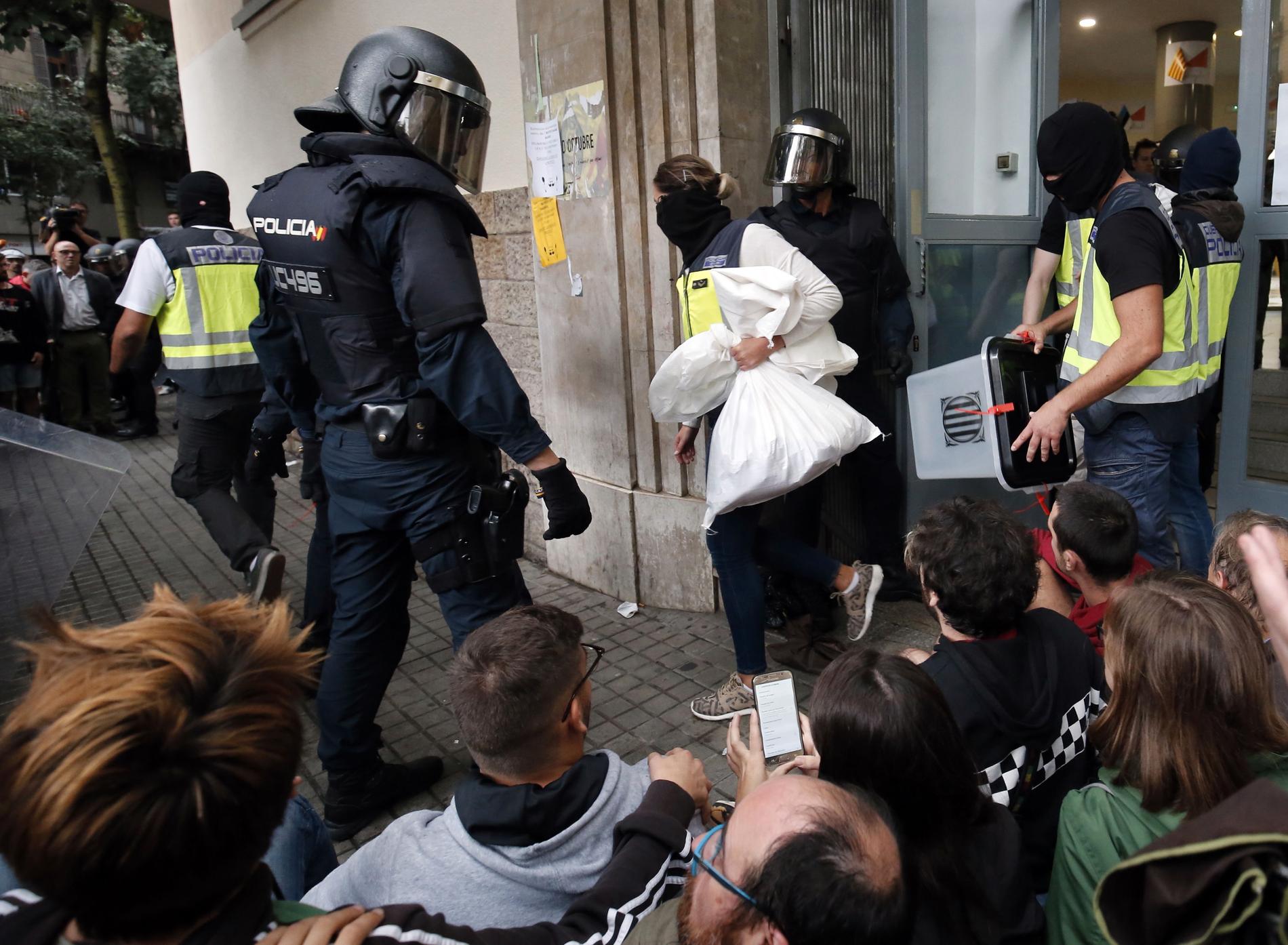 Spansk polis tar hand om valurnor i en vallokal i Barcelona.