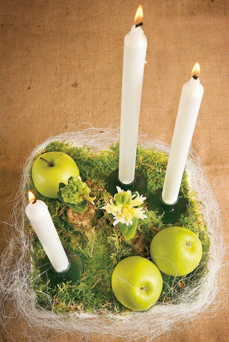 Arrangemang med äpplen och ljus. Stearinljus och vackert vintergröna äpplen blir med mycket enkla medel ett stämningsfullt arrangemang.