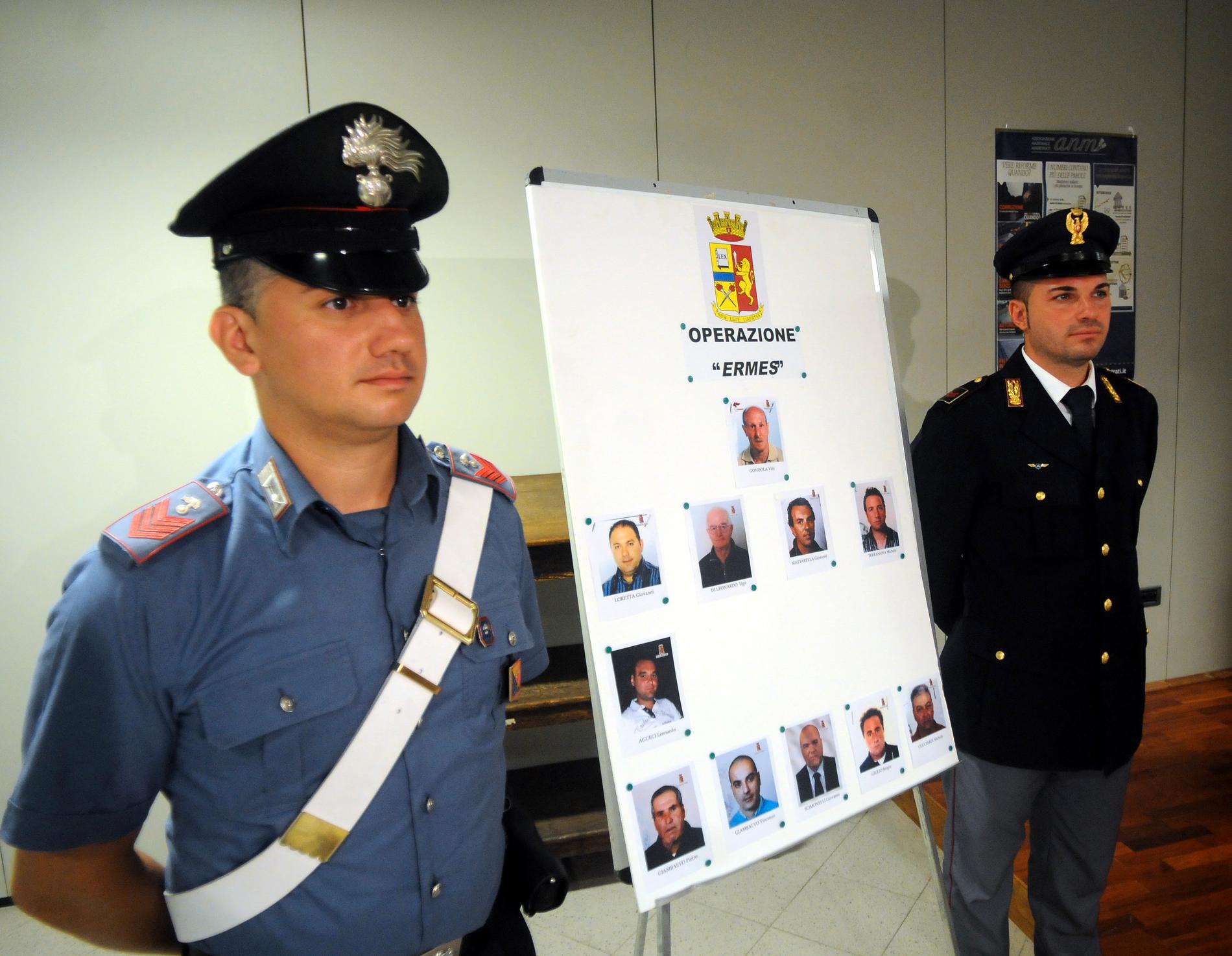Italiens polis intill ett plakat med foton på personer som misstänkts ha hjälpt sicilianska maffian. Arkivbild.