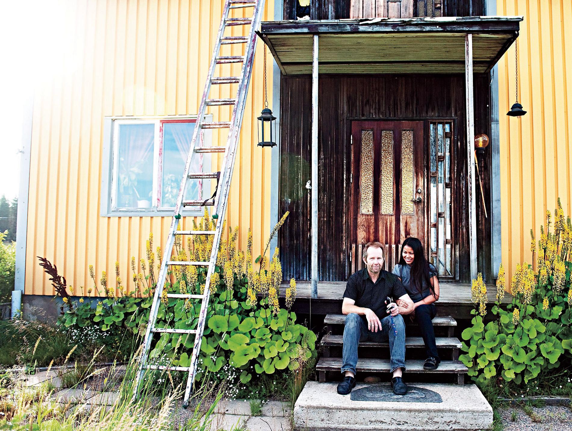 LYCKAN ÄR GUL. Glenn Lundström och Cao Sittikan utanför sitt gemensamma hus i Lansjärv. Ett medelstort hus kostar runt 100 000 kronor här, då får du ett vanligt ”Per-Albin-hus” med egen gård och en hektar mark till.