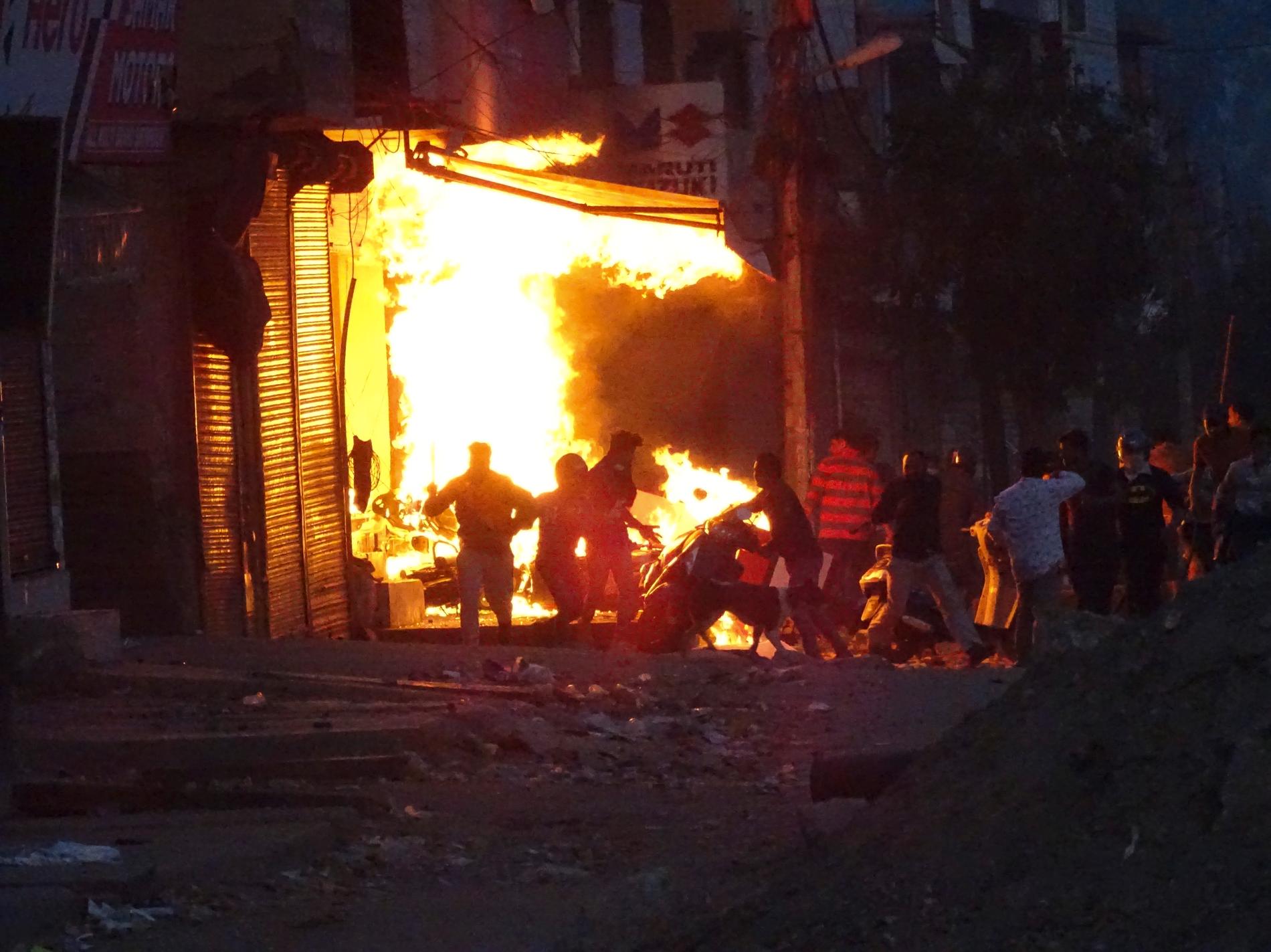 En butik sätts i brand av demonstranter under de våldsamma sammandrabbningarna i New Delhi under tisdagen.