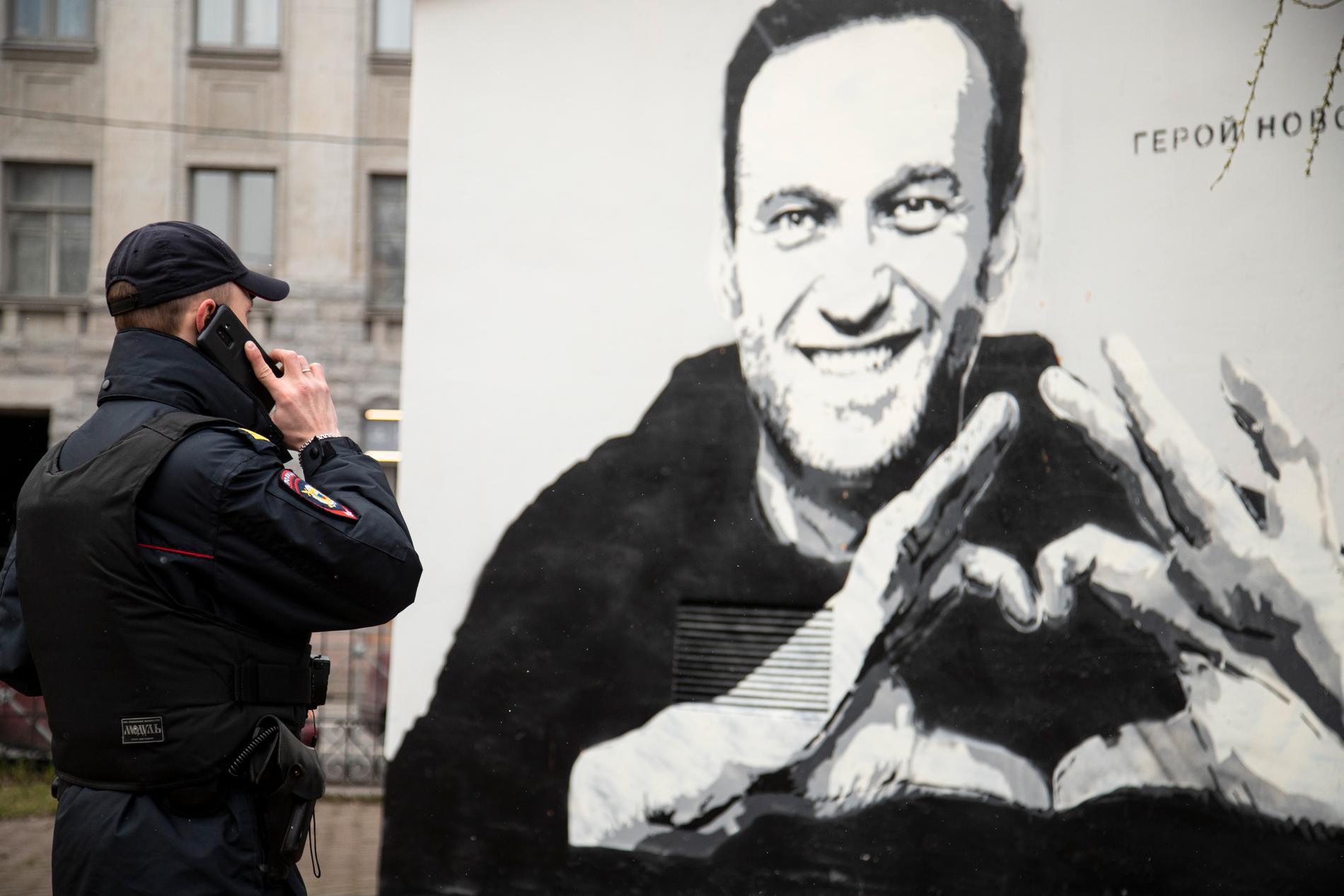 En polis i S:t Petersburg vid en väggmålning av oppositionspolitikern Aleksej Navalnyj. Arkivbild.