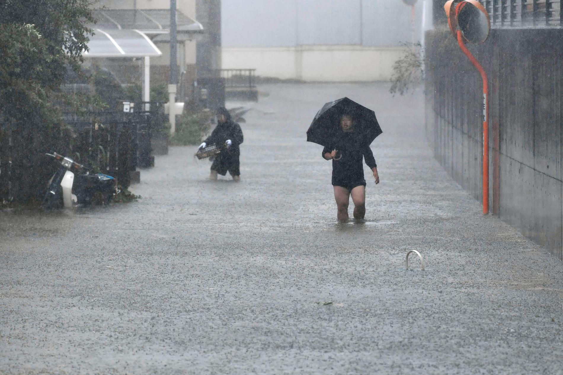 Människor går på de översvämmade gatorna i prefekturen Shizuoka i den centrala Japan.
