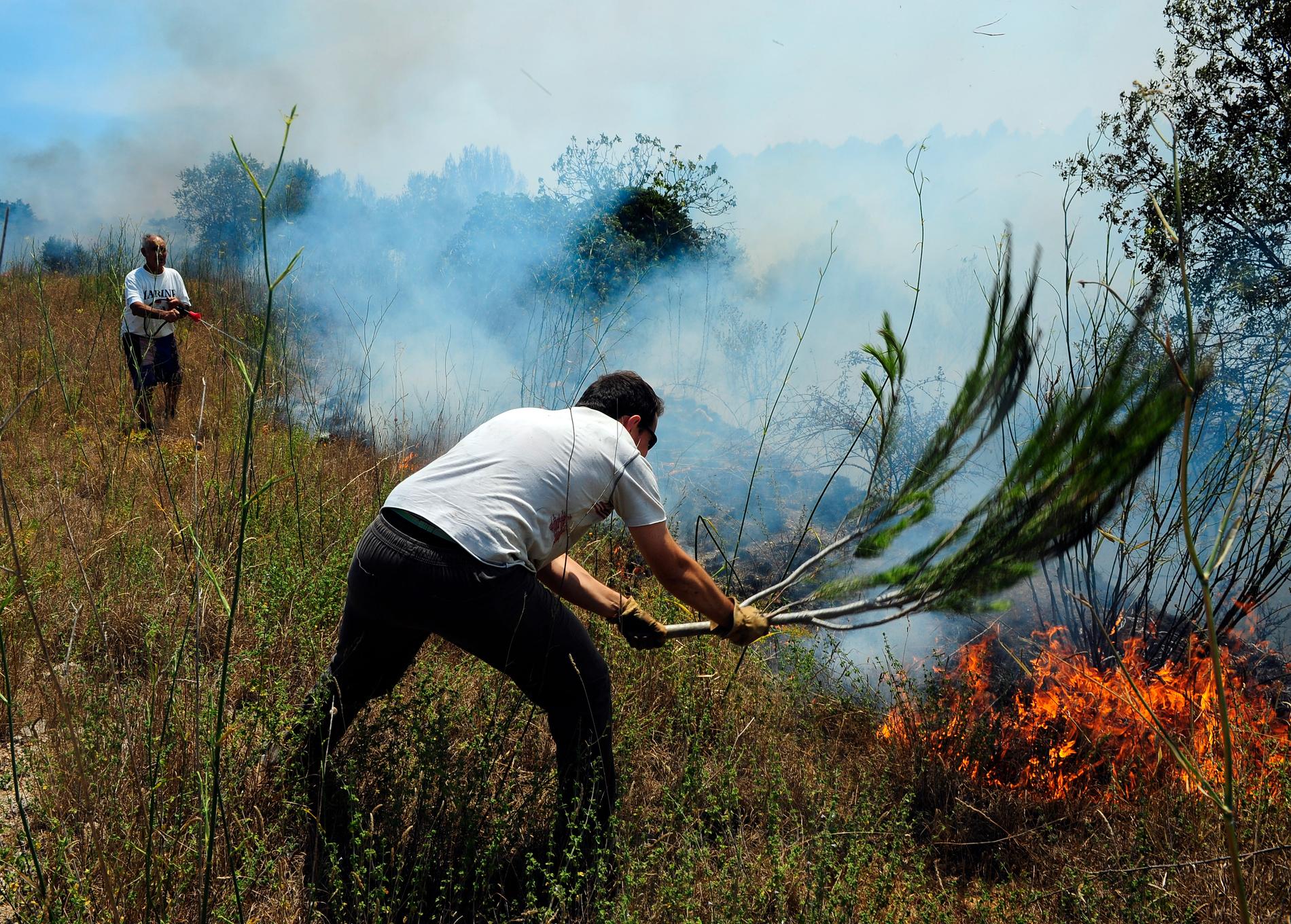 Lantbrukare försöker släcka en eld i Llers i Spanien i slutet av juli förra året.