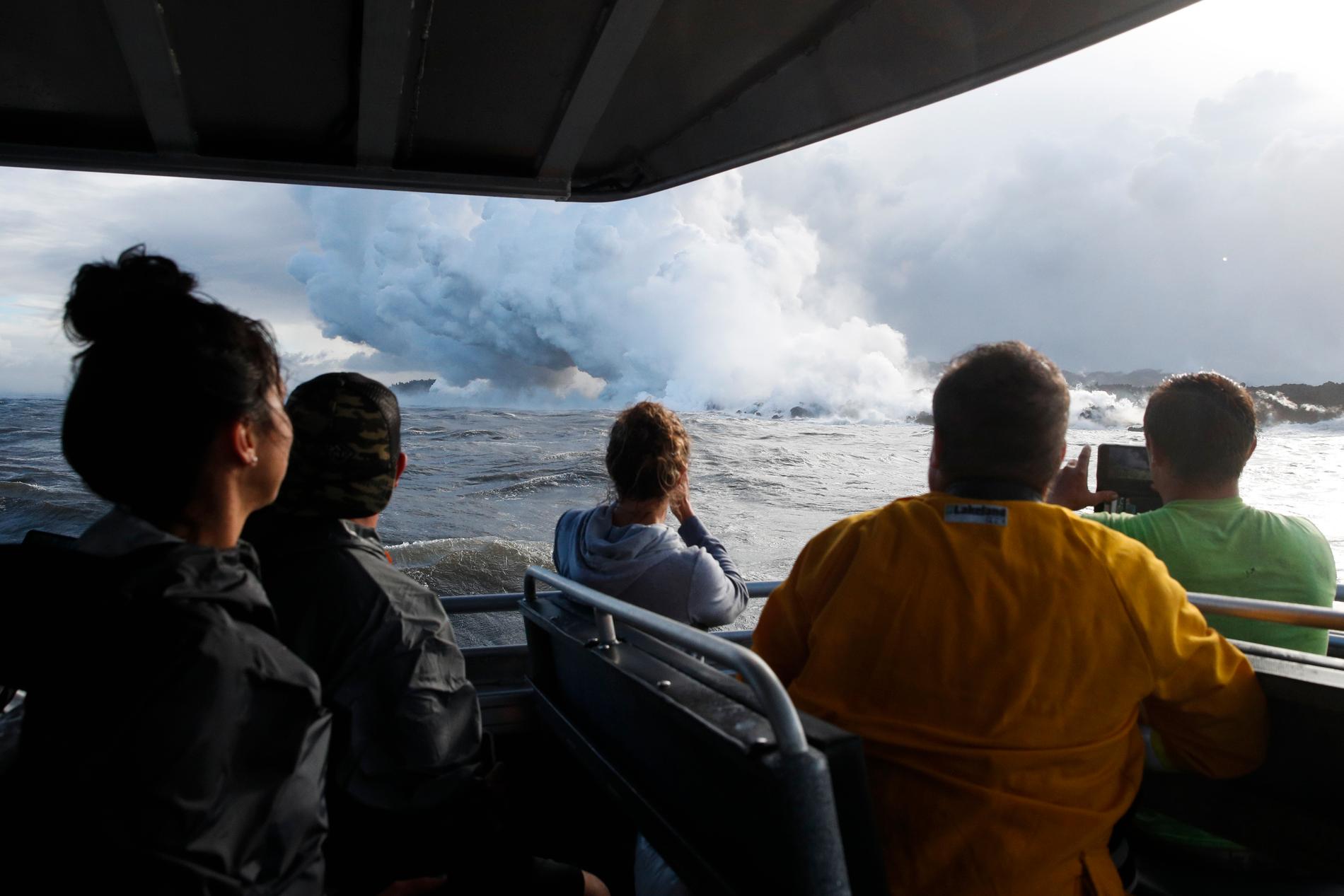 Bild från den 20 maj i år när turister passerar lavan från vulkanen som flyter ner i havet.