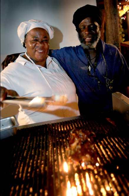 På en glödhet kolgrill lagar Marlene Alexander delikat kyckling vid vägkanten i Crown Point på karibiska ön Tobago. Wolde Selassie, skivförsäljare och affärs-granne, garanterar att det är öns godaste.