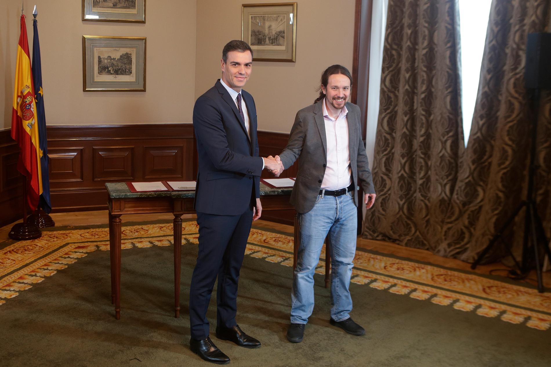 Spaniens tillförordnade premiärminister Pedro Sánchez (tv) med Unidas Podemos-ledaren Pablo Iglesias efter att ha skrivit under en pakt om att bilda en koalitionsregering.