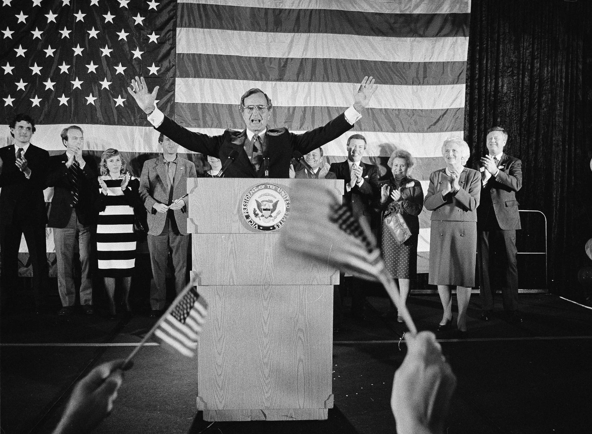 n this Nov. 7, 1984 file photo, flag-wavers greet Vice President George Bush after he was re-elected to the post of vice president, in Houston, Texas. The vice president's wife Barbara Bush is seen second from right. 
